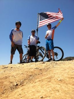 three guys on bike by flag
